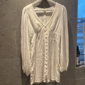 Vit kortklänning med knappar från Nelly - Supersöt vit kortklänning från Nelly i storlek 34. Jag säljer klänningen då jag endast använt den en gång vilket var på skolavslutningen! klänningen kostar 499kr igentligen men säljer för 220kr +frakt🫶🏼🫶🏼