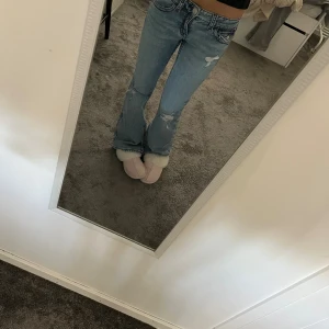 Lågmidjade blå jeanse men vinröda sömmar - Ett par blåa jeans från Gina Tricot i storlek 164 och de har vinröda sömmar. De är aldrig använda så de är i helt nytt skick! Fickor med knappar där bak. Fri frakt