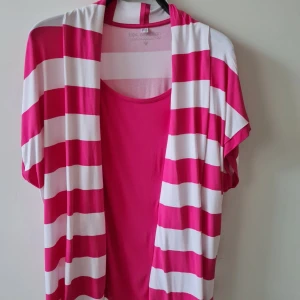 Randig topp från Bonprix strl 52/54 - Säljer en topp från Bonprix bpc collection i rosa och vitt med breda ränder. Toppen har korta ärmar och är tillverkad i mjuk viskosblandning med lite stretch. Storlek EUR 52/54. Kan hämtas i Vallentuna.