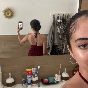 Vinröd spetsklänning med öppen rygg - Vinröd kortklänning med halterneck och öppen rygg. Överdelen är i vacker spets med knyt i nacken och kjolen är i ett lätt, flowy tyg. Perfekt för dig som vill sticka ut med en elegant och ungdomlig look.