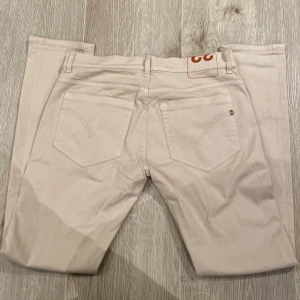 Beige skinny jeans från dondup - Snygga beige skinny jeans från Dondup med klassisk femficksdesign och diskreta nitar. Byxorna har en smal passform och är tillverkade i bomullsmix för en bekväm känsla. Perfekta för dig som gillar stilrena och ljusa jeans. Jeansen är helt nya utan prislapp