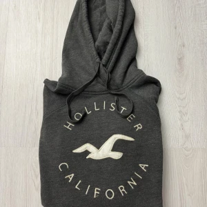 Hollister Hoodie - Säljer en riktigt fet Hollister Hoodie för en bra peng, tröjan är knappt använd och har inga defekter. Har en unik färg och ett riktigt snyggt tryck | Storlek: S/XS | Skick: 9/10 | Pris: 349kr