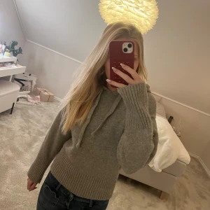 Grå stickad hoodie med huva - Mysig grå stickad hoodie med huva och snörning. Ärmen har åkt upp lite på ena sidan. 🩶
