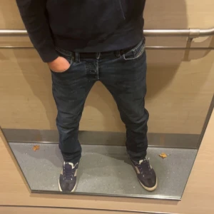 Mörkblå Diesel Safado jeans W30 L32 - Säljer ett par mörkblå Diesel Safado jeans med snygga slitningar och klassiska detaljer. Jeansen har raka ben, normal passform och fem fickor. Materialet är stretchigt denim som sitter skönt och följer kroppen. Perfekta för dig som gillar en stilren look.