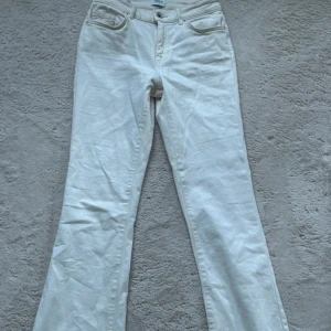 Cream vita bootcut jeans från ONLY - Snygga cream vita jeans från ONLY med bootcut-modell och klassisk femficksdesign. Jeansen har normalhög midja och är tillverkade i mjuk bomull med lite stretch för extra komfort. Perfekta för dig som vill ha en fräsch och stilren look.