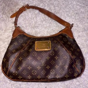 Brun Louis Vuitton axelväska  - Säljer nu min fina Louis Vuitton väska! Den är verkligen i otroligt bra skick, och säljer då den ej kommer i tillräckligt god användning och tänker att någon annan kommer ha större användning av den. Köpte den på Vestiare för cirka 6700kr och säljer för 5500kr. Ända defekten är den lilla pricken som är inuti väskan som jag inte vet om den går bort eller inte. Men den syns aldrig imed att man ofta har saker i väskan! Hör av er för fler frågor/bilder 😊🫶🏼