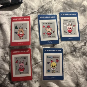 SKZSHOP HIPTAPE (HOP) Holiday Cards - Samling med fem färgglada kort med söta, handritade djurfigurer i julkläder, skapade av medlemmarna i Stray Kids. Perfekt för fans av K-pop och Stray Kids som vill ha unika samlarkort med festligt tema. Varje kort har en personlig touch och signatur. (KOMMER MED FREEBIES) (30 STYCK! SKRIV VILKEN NI VILL KÖPA!) 