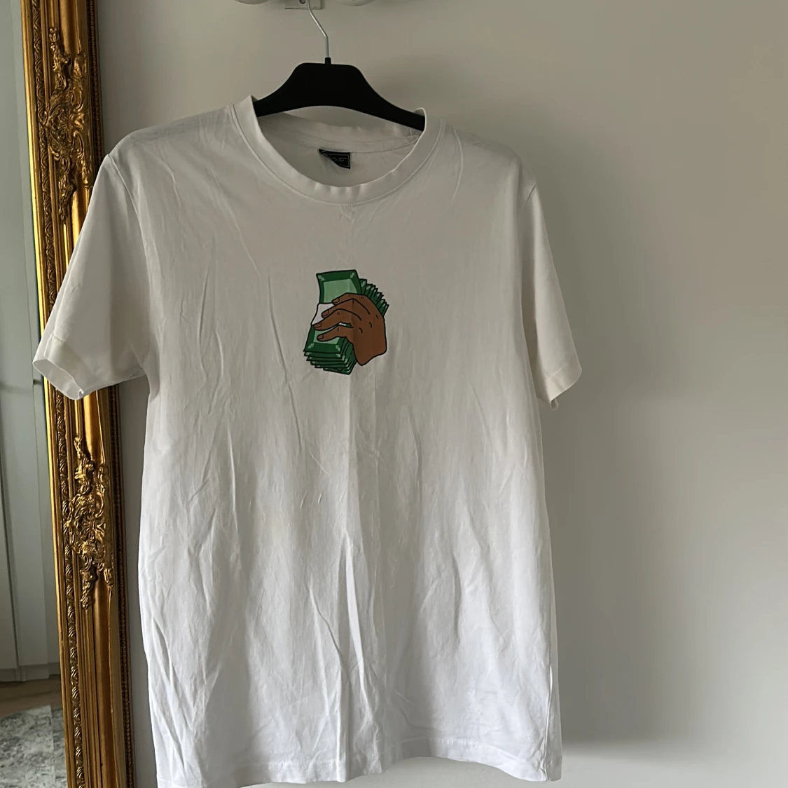 Vit t-shirt med tryck av hand och pengar