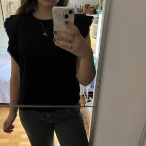 Svart blus med volang från Holly & Whyte - Svart blus från Holly & Whyte från Lindex med snygga volangdetaljer. Blusen är jätteskön och kan lätt kläs upp till en festblus! Toppen är använd fåtal gånger ca. 5 och är i superbra skick! 🩷