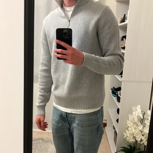 Stickad tröja  - Superfin ljusgrå stickad tröja med halv dragkedja vid kragen – perfekt för både vardag och jobb. Klassisk, tidlös modell som är lätt att matcha med jeans eller chinos. Tröjan är helt ny och aldrig använd, i storlek S. Mjukt och skönt material som ger en lyxig känsla. Inga defekter eller märken.  Ny pris är 699