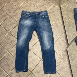 Blå jeans från Dondup, storlek 29 - Snygga blå jeans från Dondup, tillverkade i Italien. Klassisk femficksmodell med ljus tvätt och subtila slitningar. Jeansen har raka ben och normal passform, med detaljer som metallknapp och Dondup-logga på bakfickan. Perfekt för dig som gillar stilrena jeans.