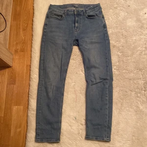 Blå slim fit jeans från Dressmann - Säljer ett par blå slim fit jeans från Dressmann. Jeansen är i mjukt denimtyg och har en snygg tvättad look. Perfekta för dig som gillar en stilren och enkel jeansstil.