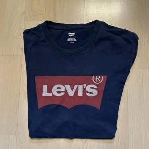 Levi's blå t-shirt - Mörkblå t-shirt med Levis logotyp tryckt på framsidan.