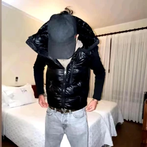  Moncler cardigan/jacka - Svart pufferjacka från Moncler med glansig finish och stor huva. Jackan har dragkedja framtill, långärmade svarta ärmar i mjukt material och Moncler-logga på vänster arm. Perfekt för dig som gillar streetwear och vill ha en jacka som sticker ut.