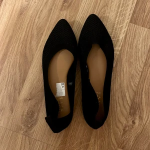 Svarta spetsiga ballerinaskor i stickat - Svarta ballerinaskor med spetsig tå och platt sula. Sann i storlek, använd 1 gång 