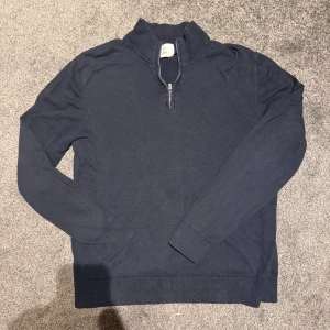 Mörkblå half zip tröja från bläck - Mörkblå långärmad tröja från Bläck med half zip-dragkedja och ståkrage. Tröjan är i bomull och har en klassisk, normal passform. Perfekt att bära över en skjorta för en clean och stilren look. Den vita pricken på första bilden var bara lite bommul eller nått som jag tog bort.  Jag är 180 och passar perfekt  storlek medium, orginal priset är 699kr 