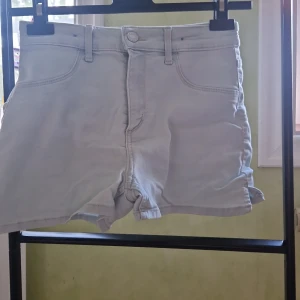 Ljusblåa jeansshorts från H&M - Säljer ett par ljusblåa jeansshorts från H&M i storlek 152. Modellen är klassisk med fem fickor, bälteshällor och knapp- samt dragkedja framtill. Perfekta för varma dagar och har en enkel, stilren look som funkar till det mesta.