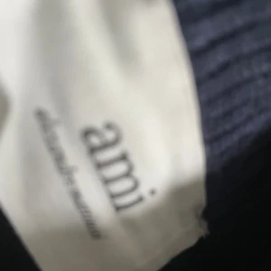Mörkblå stickad tröja från Ami - Säljer en mörkblå stickad tröja från Ami Alexandre Mattiussi med ett stort vitt hjärta och A-logga på bröstet. Tröjan har ribbade muddar vid hals, a,k opi ärmslut och nederkant. Perfekt för dig som gillar stilrena och trendiga plagg. 649 styck 
