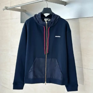 Mörkblå hoodie från Miu Miu med snörning - Snygg mörkblå hoodie från Miu Miu med dragkedja och huva i glansigt material. Röd snörning med vita detaljer och guldfärgad detalj på snöret. Fickor framtill och diskret logga på bröstet. Perfekt för dig som gillar streetstyle och exklusiva märken.