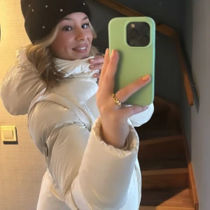 Vit pufferjacka från Michael Kors - Snygg vit pufferjacka från Michael Kors med stor huva och logga tryckt på kanten. Jackan har guldiga knappar och avtagbara ärmar så det lätt kan bli en väst. Storleken är 14 år (158cm) men jag som är 163cm och vanligtvis har 36/38  eller S på jackor passar bra i den. 