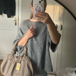 Grå stickad tröja med trekvartsärm - Mysig grå stickad tröja med avslappnad passform och trekvartsärmar. Perfekt för lager-på-lager och chill dagar. Enkel design som funkar till jeans eller kjol. Supermjuk och skön att ha på sig.