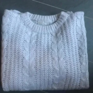 Ljusgrå stickad tröja Nuova Moda - Supermysig ljusgrå stickad tröja från Nuova Moda med klassiskt flätmönster. Rund halsringning och långärmad modell med loose passform. Perfekt för dig som gillar chill och oversized vibe. Materialet är mjukt och värmande, passar extra bra när det är kallt ute.oanvänd 