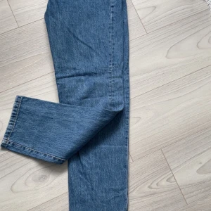 Blå jeans från Woodbird, straight fit - Snygga blå jeans från Woodbird i klassisk straight fit. Jeansen har normal passform och är tillverkade i slitstarkt denim med tydliga sömmar. Perfekt för dig som gillar enkel och stilren look. Storlek 31/32.