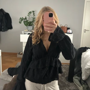 Svart blus med volanger - Säljer en svart v ringad blus med volanger från Gina tricot i storlek M men passar även S. Inte använd många gånger och inga defekter💕💕