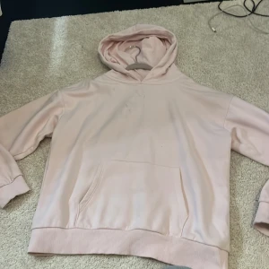 Ljusrosa hoodie från Gina Tricot - Säljer en ljusrosa hoodie från Gina Tricot i storlek 146/152. Tröjan har en klassisk huva, magficka och ribbade muddar vid ärmslut och nederkant. Perfekt för chill dagar och enkel att matcha med jeans eller leggings.