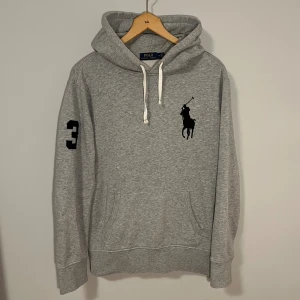 Grå Ralph Lauren Big Pony Hoodie  - Asfet och sällsynt Big Pony Hoodie från Ralph Lauren. Storlek M. Fint skick förutom två mindre defekter som man inte tänker på (sista 2 bilderna). Hör gärna av er vid funderingar🙌🏻🙌🏻