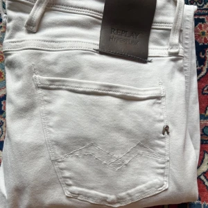 Vita Replay Hyperflex jeans - Säljer ett par vita Replay Hyperflex jeans med klassisk femficksdesign och snygg passform. Jeansen är stretchiga och sitter slim längs benen. Perfekta om du vill ha ett par stilrena och bekväma jeans med modern look.