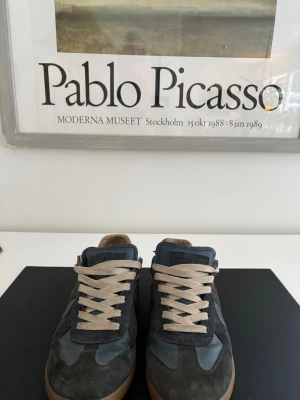 Maison margiela - Snygga mörkblå Masion Margiela med beige snörning och brunasulor. Skorna har en mix av mocka och slätt läder i ovandelen, vilket ger en schysst kontrast. Perfekta för dig som vill sticka ut i mängden och inte se ut som alla andra. Hör av vid fundering 💭 priset inte hugget i sten!