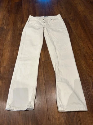 Vita raka jeans - Säljer ett par vita jeans med rak passform och klassisk femficksdesign. Jeansen har normal midja och är tillverkade i ett mjukt bomullstyg. Perfekta för dig som vill ha en clean och stilren look.