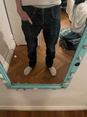 Mörkblå straight jeans - Säljer ett par mörkblå straight jeans med låg gren och raka ben. Jeansen har klassiska fem fickor och tydliga sömmar. Perfekta för en avslappnad streetstil och passar dig som gillar en lösare passform.