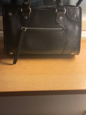 Svart handväska med silverdetaljer - Snygg svart handväska. Köpt på Vinted och tror märket är hm. Inga tecken på användning, ser ny ut. Pris går att diskutera💕