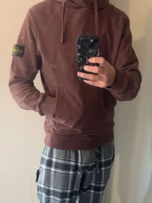 Brun hoodie från Stone Island - Säljer en brun hoodie från Stone Island med klassisk patch på vänster ärm. Den är i bra skicka och köpt för 3800 kr. En liten defekt som knappt syns på fickan därför billigt pris.