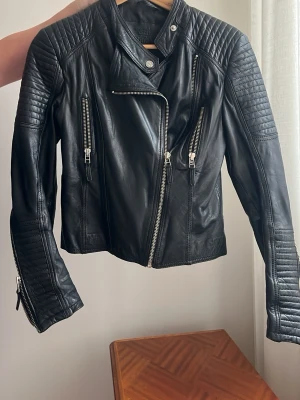 Svart biker skinnjacka  - Svart skinnjacka i bikerstil med quiltade detaljer på axlar och ärmar. Jackan har en 2016 stil  från Primeboots