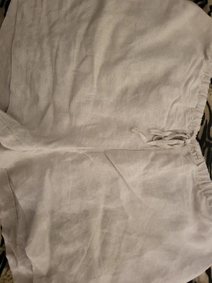 Beiga linneshorts med snörning - Luftiga och sköna beiga shorts i linne med snörning framtill. Perfekta för varma dagar och enkel att matcha med olika toppar. Avslappnad passform och stilren design. Använda ca 2 gånger