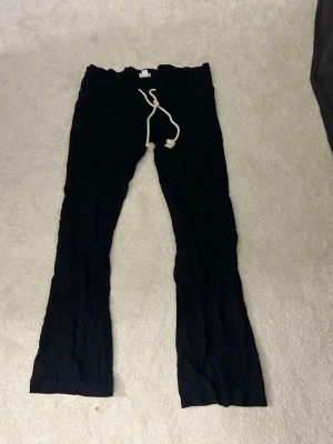 Svarta linnebyxor med snörning - Säljer ett par svarta linnebyxor med avslappnad passform och vit dragsko i midjan. Byxorna har raka ben och är perfekta för en chill och stilren look. Materialet är luftigt linne som passar bra till sommaren.