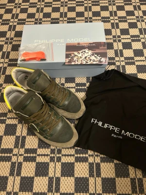 Gröna Philippe Model sneakers - Snygga sneakers från Philippe Model i grönt med detaljer i mocka, mesh och läder. Skorna har bruna skosnören, beige sula och gul detalj vid hälen. Kommer med originalkartong, extra skosnören och dustbag. Perfekta för dig som gillar streetstyle och exklusiva märken.