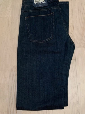 Mörkblå jeans från Replay med prislapp  - Snygga mörkblå jeans från Replay med klassisk femficksdesign och kontrastsömmar. Jeansen har raka ben och är tillverkade i ett slitstarkt denimtyg. Perfekta för dig som gillar en tidlös och stilren look. Modell: WV594. Nytt pris: 1199. Mitt pris:290
