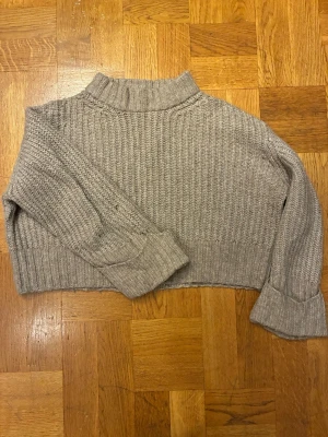 Beige stickad tröja Gina Tricot - Mysig beige stickad tröja från Gina Tricot med hög krage och breda ribbade muddar. croppad passform. 