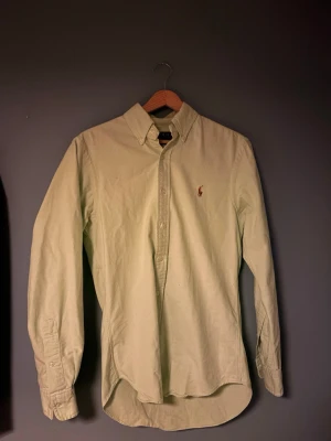 Ljusgrön skjorta från Polo Ralph Lauren - Snygg ljusgrön skjorta från Polo Ralph Lauren i slim fit-modell. Skjortan har klassisk krage, knappar framtill och broderad logga på bröstet. Tillverkad i stretchig bomull för extra komfort. Perfekt för en stilren look.skriv om ni har några frågor eller om ngn annan bild.
