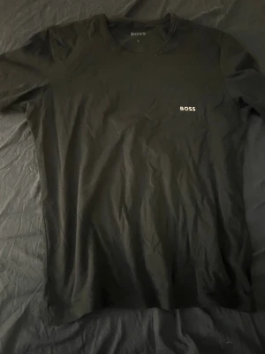 Svart t-shirt  - En stilren svart t-shirt  med diskret logga på bröstet. Klassisk rund halsringning och normal passform. Perfekt basplagg för en enkel och snygg look.