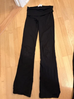 Svarta yoga pants Gina Tricot - Svarta leggings från Gina Tricot med bootcut-modell och bred midjeresår. Mjukt och stretchigt material som sitter skönt. Perfekta till en avslappnad look eller när du vill ha något bekvämt men ändå snyggt.