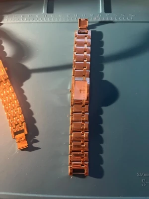 Guldfärgad klocka från Esprit - Stilren guldfärgad klocka från Esprit med fyrkantig urtavla och länkarmband i metall. Klassisk design som passar till många olika looks. Urtavlan är enkel och elegant med Esprit-loggan synlig. Behövs nya batterier 