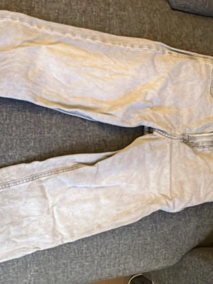 Ljusgrå raka jeans - Säljer ett par ljusgrå jeans med rak passform och klassiska bakfickor. Jeansen har en enkel design och är perfekta för en avslappnad stil. Materialet är denim och de har en normal midja.