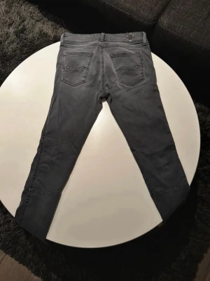 Grå Replay jeans, storlek 27,  - Säljer ett par gråa Replay Kayte jeans i storlek 27. Jeansen har fem fickor, svarta detaljer och raka sömmar över knäna för en cool look. Materialet är mjukt och stretchigt jeans-tyg som sitter snyggt och bekvämt. Perfekta till sneakers eller boots.