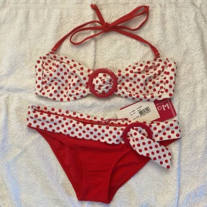 Röd och vit prickig bikini från Protest - Superfin bikini från Protest i rött och vitt med prickigt mönster. Överdelen har knyt i nacken och dekorativ ring framtill, underdelen har bred kant med rosett och ring. Perfekt för sommaren! Bikinin är helt oanvänd och har trosskydd och prislappar kvar! Pris kan diskuteras.