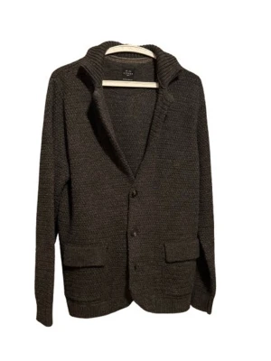 Mörkgrå stickad kofta med krage - Mysig mörkgrå stickad kofta från Fjällräven med bred krage och två stora fickor framtill. Koftan har knäppning med två knappar och en patch på ärmen. Perfekt för lager-på-lager och chill stil.